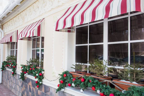 Birçok ışıltılı, parlak Noel ağacı topları, bir restoranın pencereleri üzerinde dekorasyon