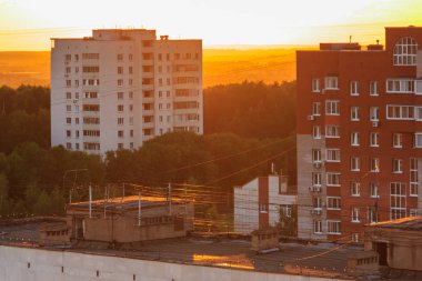 Bir kasabada gün batımı. Küçük binaların etrafındaki ağaçlar.