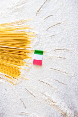Unlu beyaz arka plan üzerinde pişmemiş makarna spagetti makarna ve İtalyan bayrağı. Masada elle çizilmiş güneş ışınları, basit karikatür tarzı