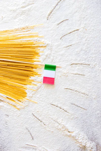 Uncooked pasta spaghetti macaroni and italian flag on floured white background. Hand drawn sun beams on table, simple cartoon style