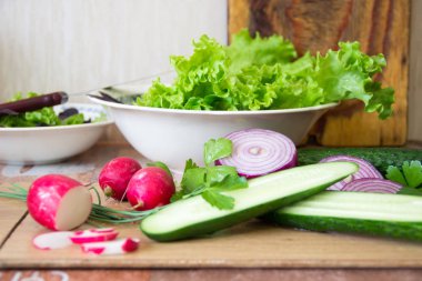 Mutfakta salata hazırlıyorum. Dilimlenmiş turp, marul, salatalık, kırmızı soğan ve taze otlar