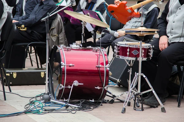 Una banda que se prepara para actuar en la calle en verano al aire libre. Conjunto de tambor marrón, guitarra roja, micrófono, otros equipos musicales . — Foto de Stock