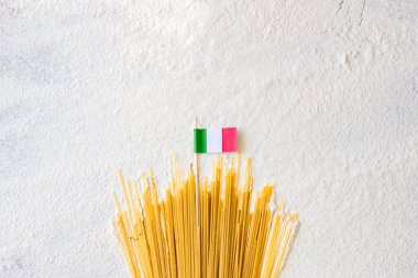 Unlu beyaz arka plan üzerinde pişmemiş makarna spagetti makarna ve İtalyan bayrağı. Metin için alan