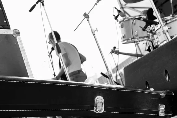 La banda musical está tocando al aire libre en el festival de verano, vista desde detrás del escenario, estuche negro para guitarra, vocalista en el escenario, foto en blanco y negro — Foto de Stock