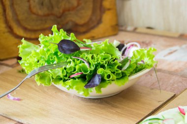 Turp, marul, kırmızı soğan ve fesleğen yaprakları ile salata hazırlanıyor. Diyet veya vejetaryen gıda kavramı