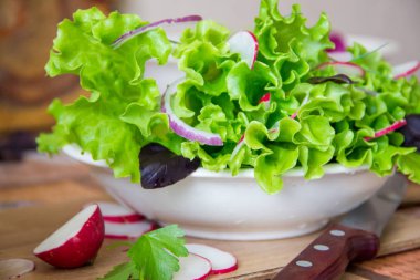 Turp, marul, kırmızı soğan ve fesleğen yaprakları ile salata hazırlanıyor. Diyet veya vejetaryen gıda kavramı