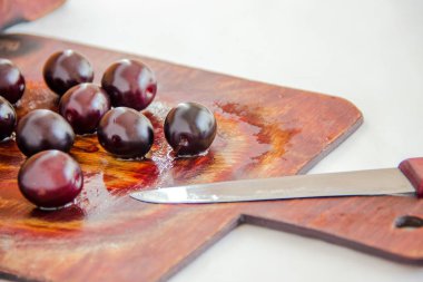 sonbahar hasat - ıslak ahşap üzerinde koyu erik, beyaz mutfak geri bir bıçak ile.