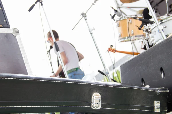 La banda musical está tocando al aire libre en el festival de verano, vista desde detrás del escenario, estuche negro para guitarra, vocalista en el escenario — Foto de Stock