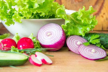 Sağlıklı vegan salata malzemeleri. Dilimlenmiş turp, marul, salatalık, kırmızı soğan ve taze otlar