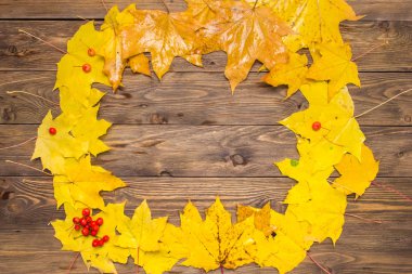 Koyu kahverengi ahşap masa arka plan üzerinde sarı ve turuncu düşmüş akçaağaç yaprakları.