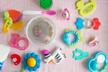 Masadaki pembe desenli bebek aksesuarları. Beslenmek için doğal sebze püresi ve ayı görüntüsüyle kaşık ve bovling. Diş çıkarma oyuncakları, kukla, krem ve termometre.