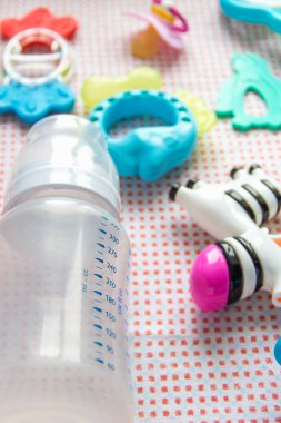 Masadaki pembe desenli bebek aksesuarları. Beslenmek için kaşık ve boş şişe. Diş çıkartan oyuncaklar, şapşal. Süper manzara.