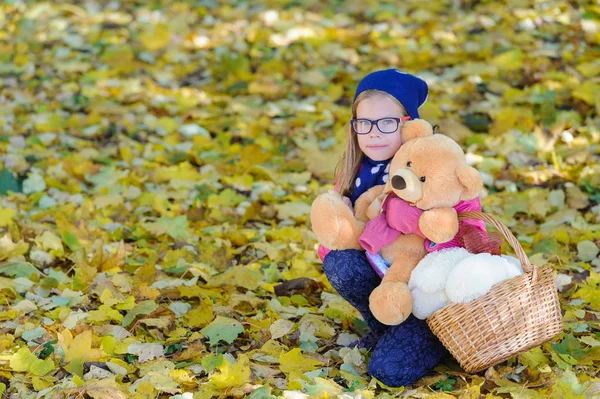Little girl with Teddy bear in autumn outdoor — Stock Photo, Image