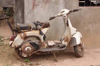 Sokaktaki eski, paslı motosiklet.
