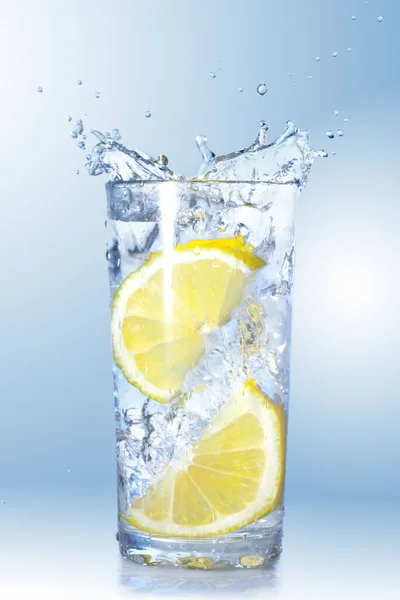 Zwei Zitronen Fielen Ein Glas Mit Wasser Auf Gefälle Hintergrund — Stockfoto