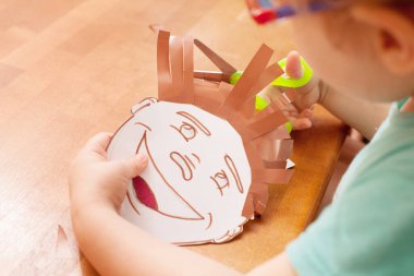 Çocuk berber dükkanında oynuyor. Çizilmiş karakterin kıllarını kesiyor. El yapımı oyun