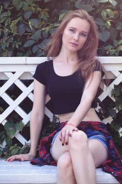 Şortlu genç bir kız ve şehirde siyah bir konu. Parlak duygular, yaşam tarzı, güneşli bir gün.