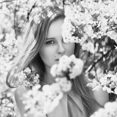 Mavi elbiseli genç sarışın bir kızın portresi. Çiçekli ağaçlar.