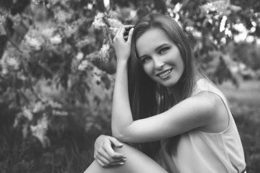 Mavi elbiseli genç sarışın bir kızın portresi. Çiçekli ağaçlar.