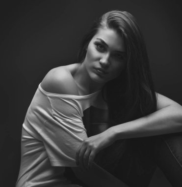 Güzel kız stüdyoda gri arka planda poz veriyor. Moda portresi. Makyaj. Uzun saçlı. Siyah-beyaz fotoğraf. 