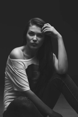 Güzel kız stüdyoda gri arka planda poz veriyor. Moda portresi. Makyaj. Uzun saçlı. Siyah-beyaz fotoğraf. 