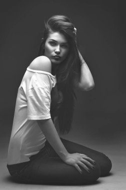 Güzel kız stüdyoda gri arka planda poz veriyor. Moda portresi. Makyaj. Uzun saçlı. Siyah-beyaz fotoğraf. 