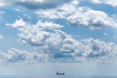 Gemi denizde yüzüyor, gökte güzel beyaz bulutlar.