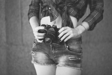 Elinde retro kamera olan şortlu bir kız.