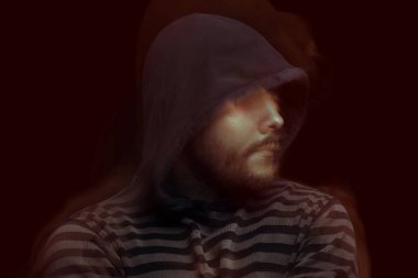 Siyah arka planda kapüşonlu bir adamın şeytani dramatik portresi.