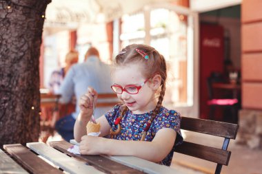 Kız bir kafede bir masaya oturur ve dondurma yer.