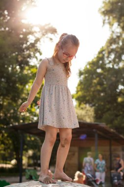 Gözlüklü genç kız oyun bahçesinde oynuyor, güneşli bir günde.