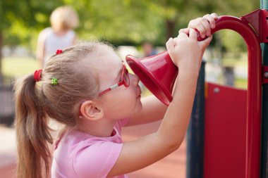 Genç kız yazın oyun parkında yürüyor ve oynuyor.