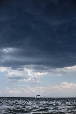 Açık denizde yalnız bir tekne, kötü hava, tehlike hissi.