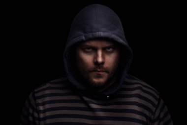 Siyah arka planda kapüşonlu bir adamın şeytani dramatik portresi.