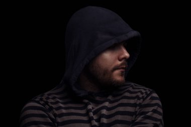 Siyah arka planda kapüşonlu bir adamın şeytani dramatik portresi.
