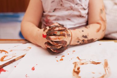 Kız masada oturuyor ve resim çiziyor. 