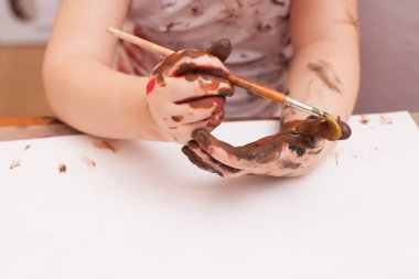 Kız masada oturuyor ve resim çiziyor. 