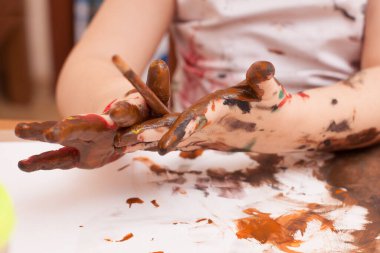 Kız masada oturuyor ve resim çiziyor. 