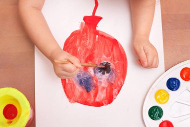 Yukarıdan bak. Çocuk bir fırça çizer ve beyaz kağıda resim yapar. balon