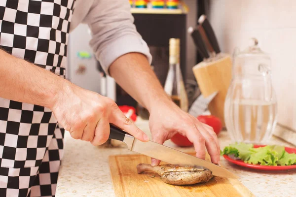 Adam mutfakta hazırlanıyor. Bıçak tavuğu parçalara ayırır.