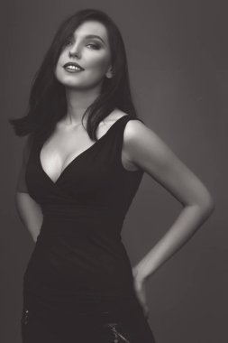 Güzel kız stüdyoda gri arka planda poz veriyor. Moda portresi. Makyaj. Siyah takım.