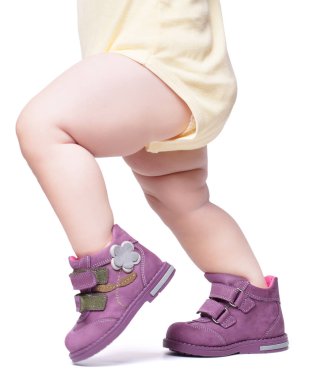 Şık bebek botların içine giriyor. Beyaz bir arka grupta izole edilmiş.