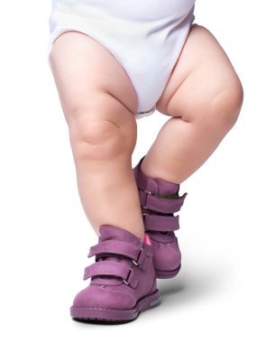 Şık bebek botların içine giriyor. Beyaz bir arka planda izole edilmiştir.