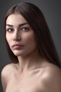 Güzel kız stüdyoda gri arka planda poz veriyor. Moda portresi. Makyaj malzemesi. Uzun saçlı. 