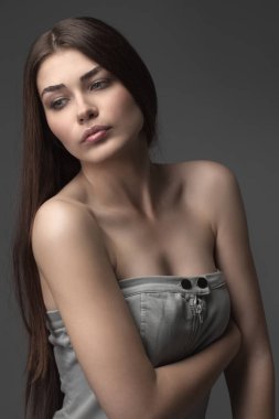 Güzel kız stüdyoda gri arka planda poz veriyor. Moda portresi. Makyaj malzemesi. Uzun saçlı..