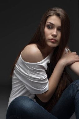 Güzel kız stüdyoda gri arka planda poz veriyor. Moda portresi. Makyaj malzemesi. Uzun saçlı..