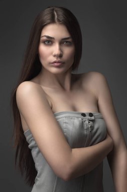 Güzel kız stüdyoda gri arka planda poz veriyor. Moda portresi. Makyaj malzemesi. Uzun saçlı..