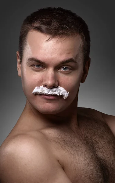 portrait of the young sexy man. without clothes, with moustaches from the foam, flirting a look