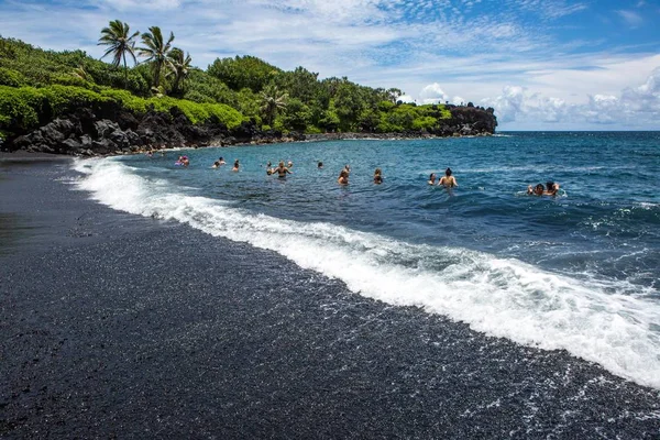 2018年6月 毛伊岛 黑沙海滩接待了一群游泳者在一个受欢迎的目的地享受冲浪的度假者和度假游客 免版税图库照片