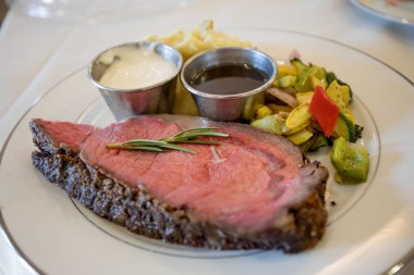 Prime kaburga sığır yan, at turp ve Au Jus ile beyaz bir plaka üzerinde bir kesim ile odak alan sığ derinliği ve biberiye delikanlı vurdu..